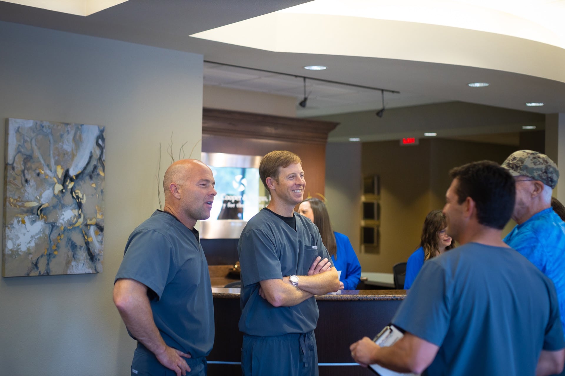 Several men in blue shirts conversing in a modern office or business reception area.