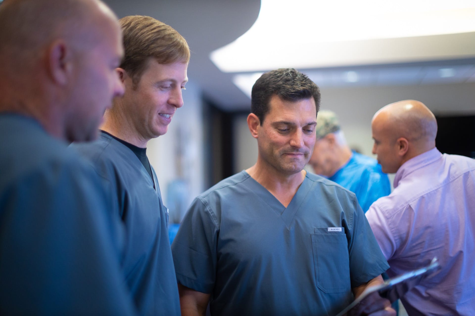 Medical professionals in scrubs engaged in discussion during hospital rounds or training session.